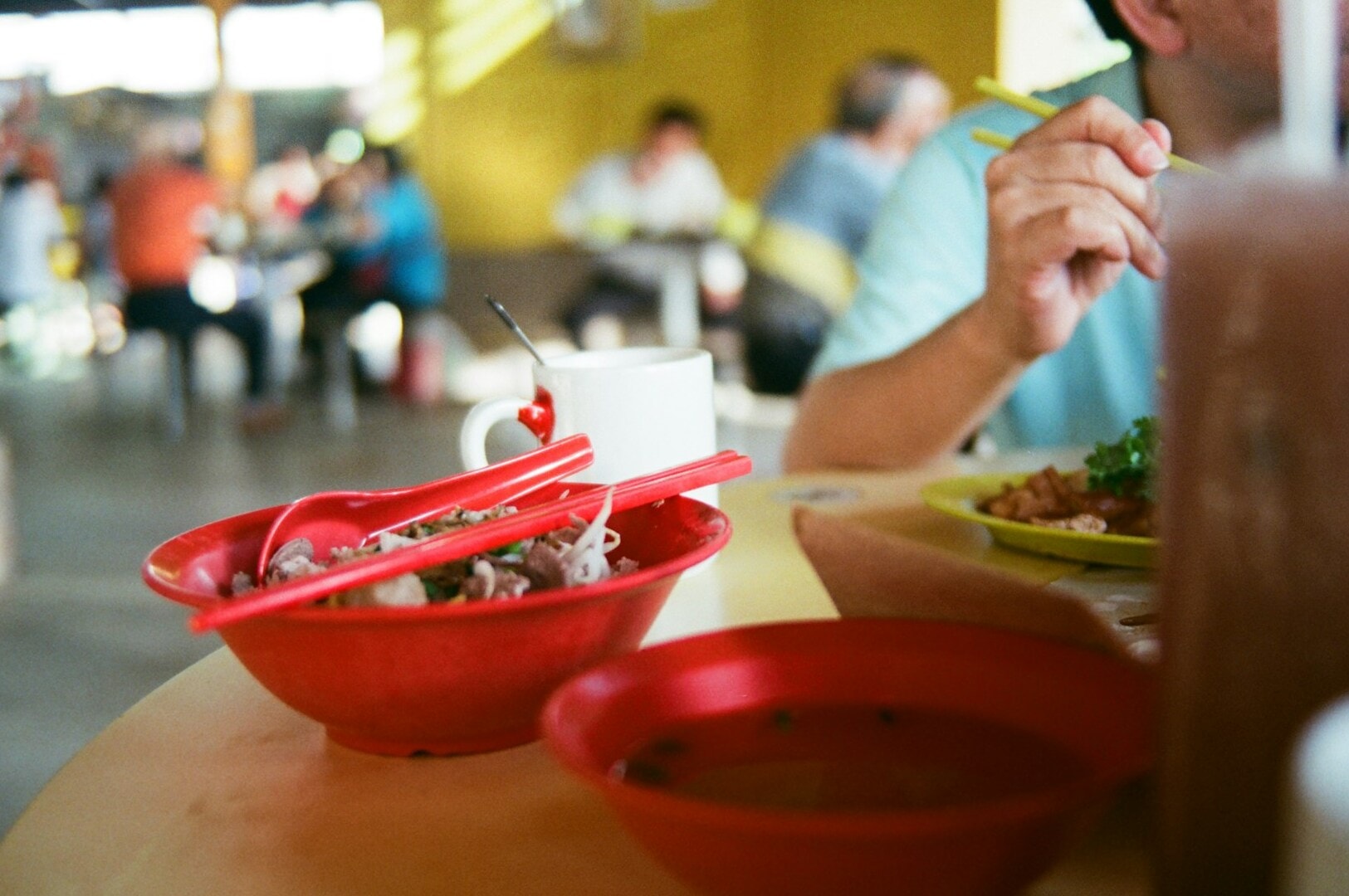 A man savoring a bowl of food in a lively Singapore Hawker Centre, showcasing the vibrant local dining scene.