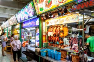 A bustling Singapore hawker market filled with people shopping and enjoying various street foods
