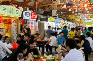 A diverse group of people enjoying a meal together at a Singapore Hawker restaurant