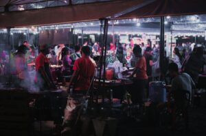 A diverse group of people enjoying food at a bustling Singapore Hawker Centre market.