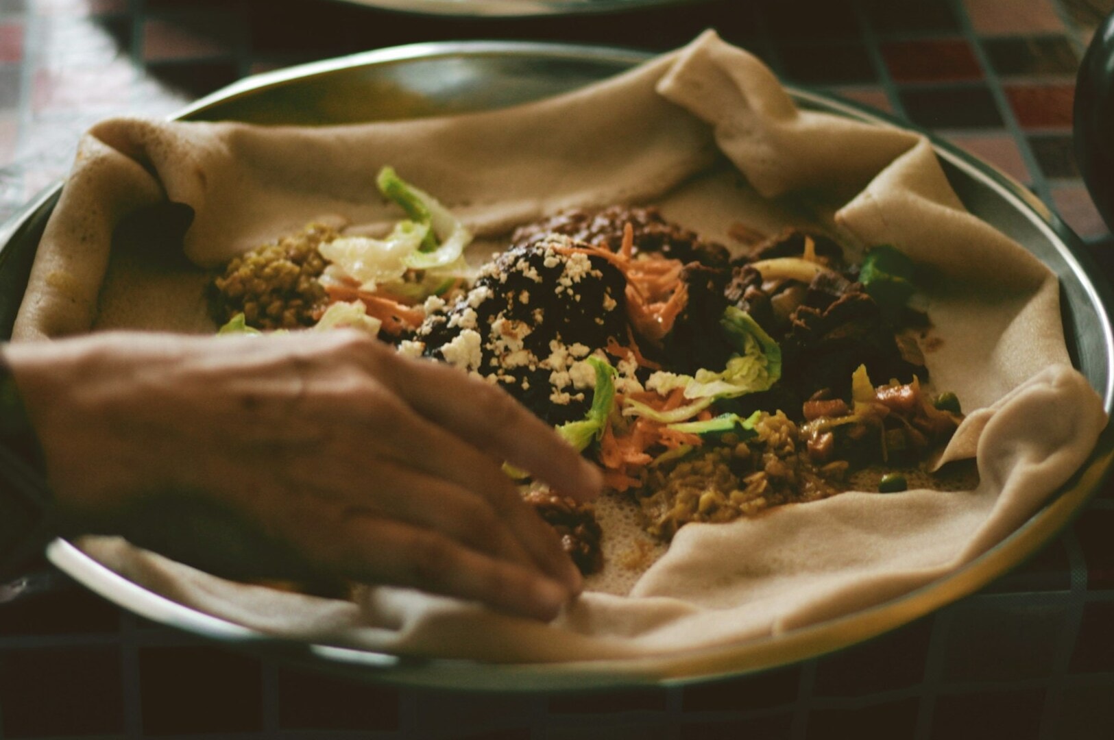 Individual extending hand towards a plate of food in a lively Singapore Hawker Centre.