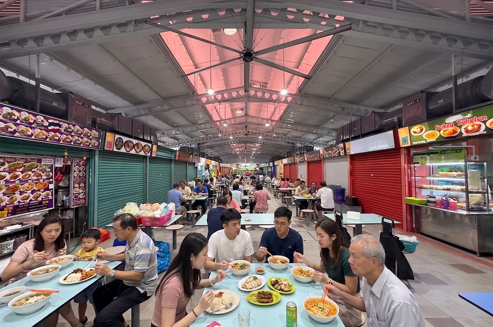 People dining at the Alexandra Village Food Centre in Singapore, featuring stalls like Sekra Pukelen.
