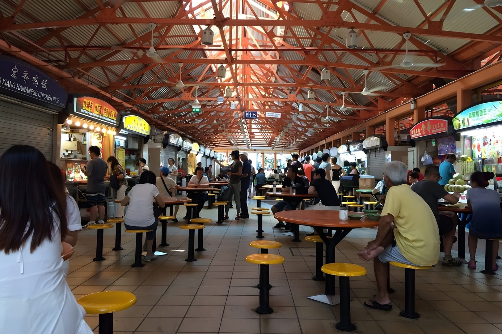 People seated at tables, savoring diverse dishes in the lively atmosphere of Singapore Maxwell Food Centre.