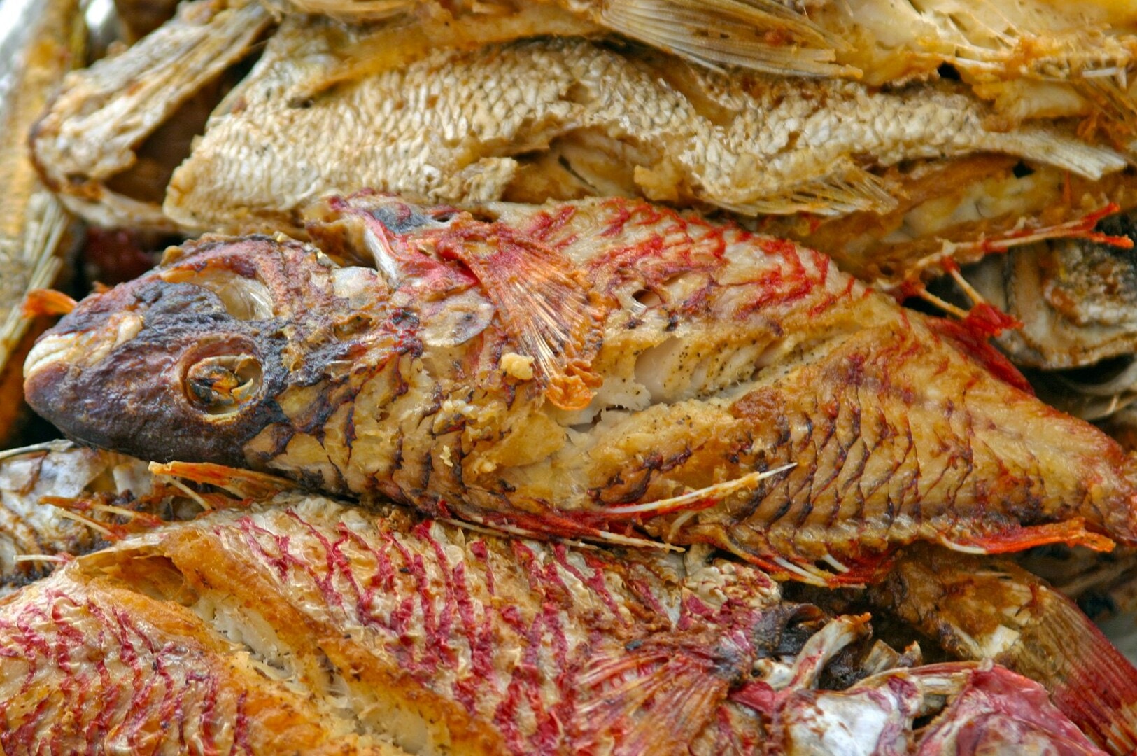 A close-up of a stack of dried fried fish on a table, highlighting their crispy appearance and rich, golden hue.