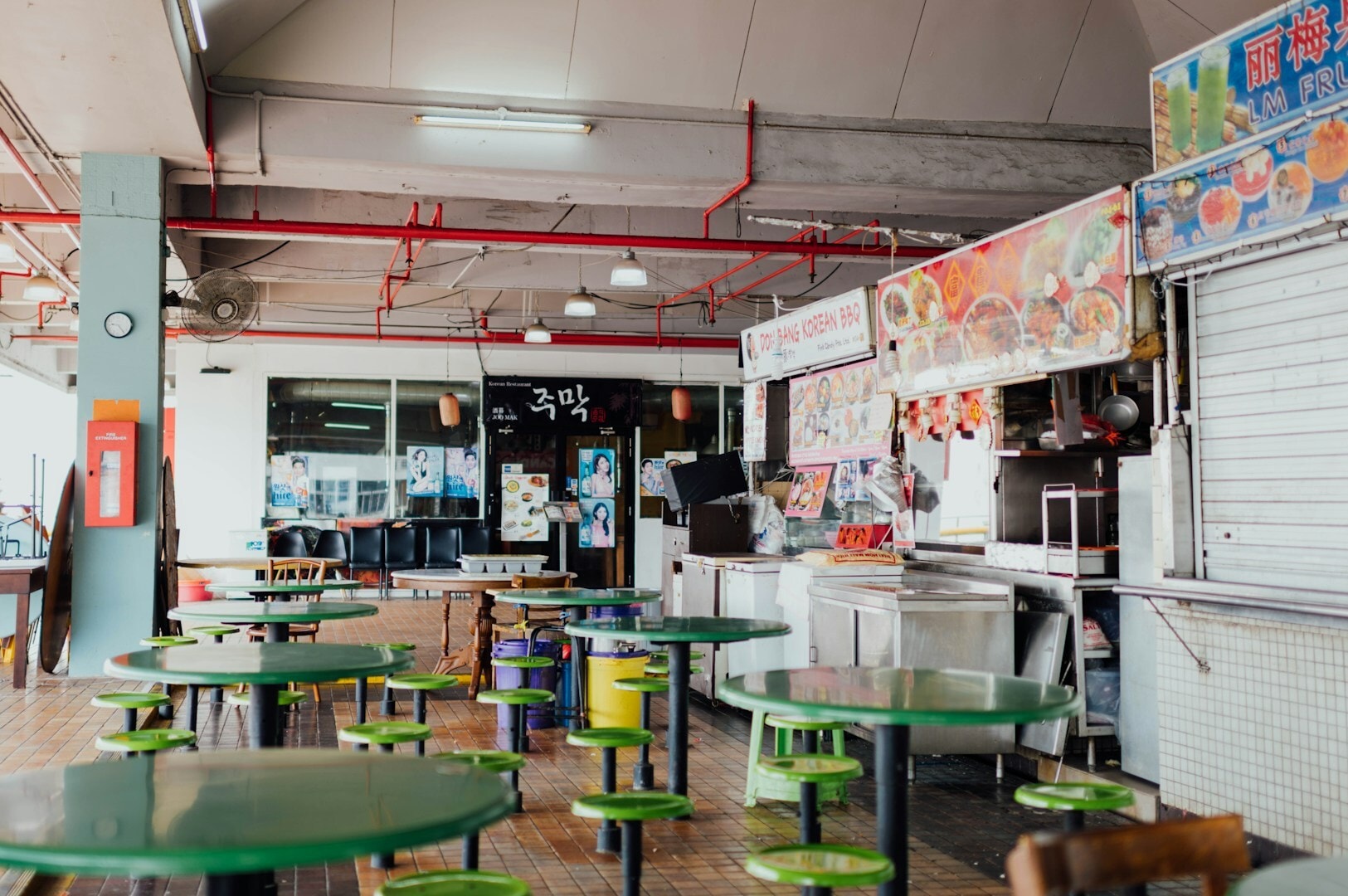 Interior of a Singapore Hawker Centre with rows of tables and chairs, filled with patrons savoring diverse cuisines.