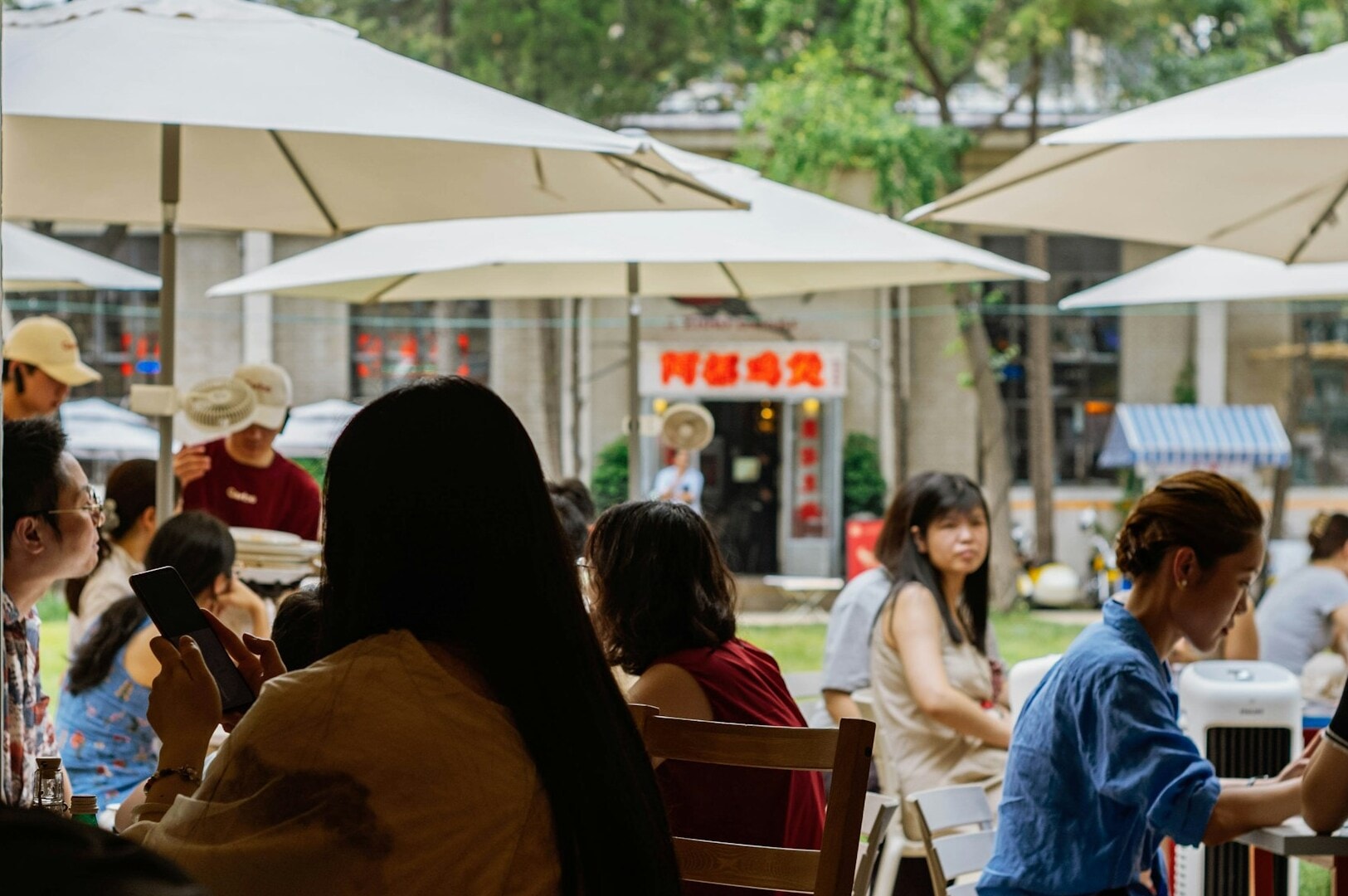 Patrons seated at tables with umbrellas in a vibrant outdoor setting of Singapore Hawker Stalls.