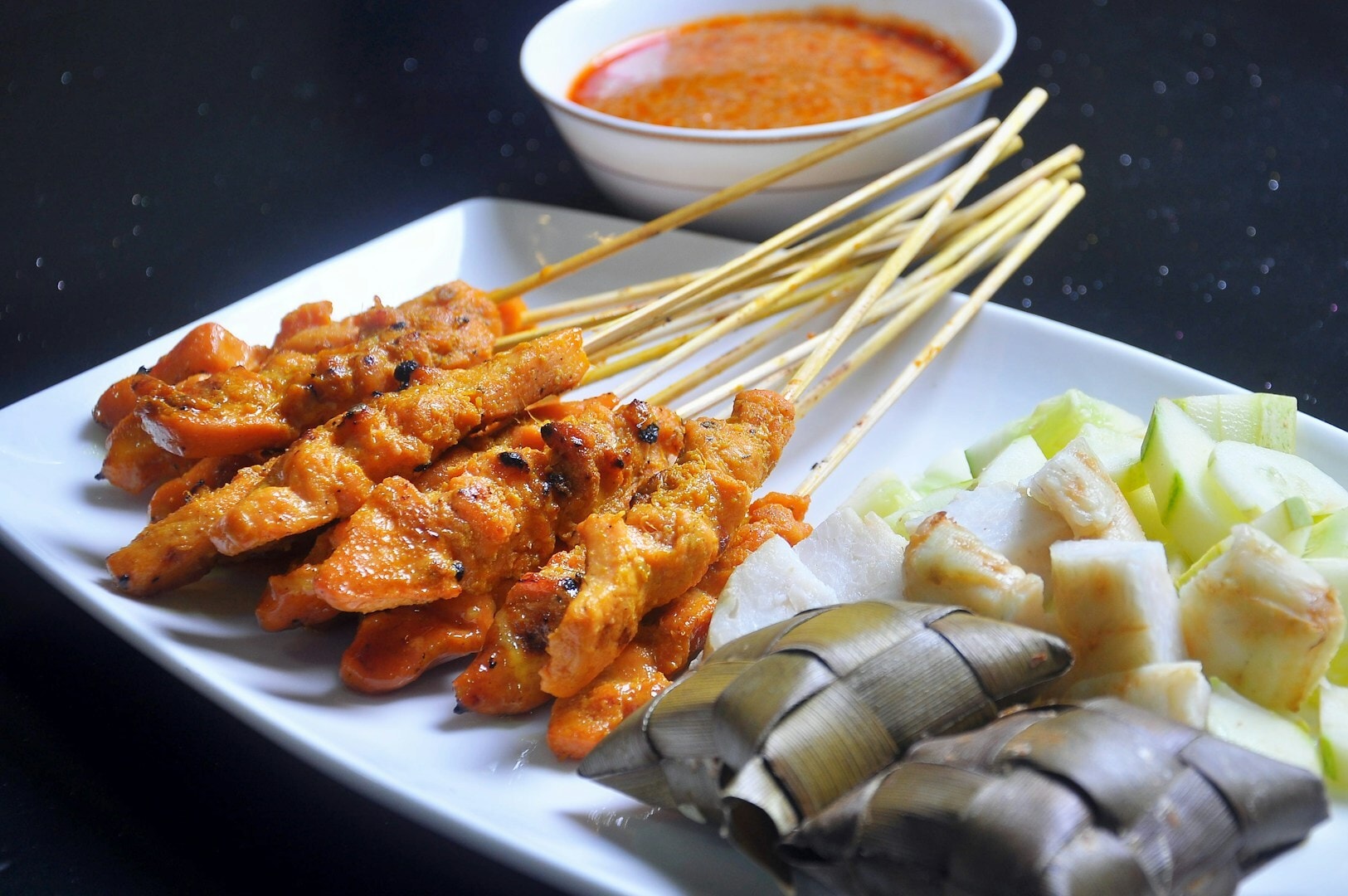 A serving of satay on a plate, featuring skewers of meat and assorted grilled vegetables, ready to be enjoyed.