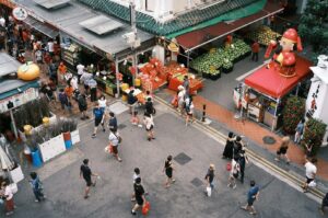 Crowded aerial view of a Singapore Hawker Centre, showcasing people navigating through various food stalls and vendors.