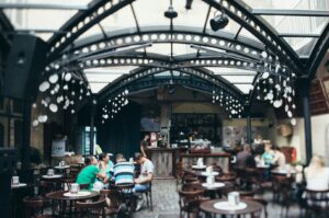 Diners seated at tables in a vibrant outdoor cafe setting at a Singapore Hawker Centre, surrounded by food stalls.