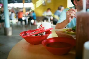 A man enjoying a bowl of food at a bustling Singapore hawker center restaurant