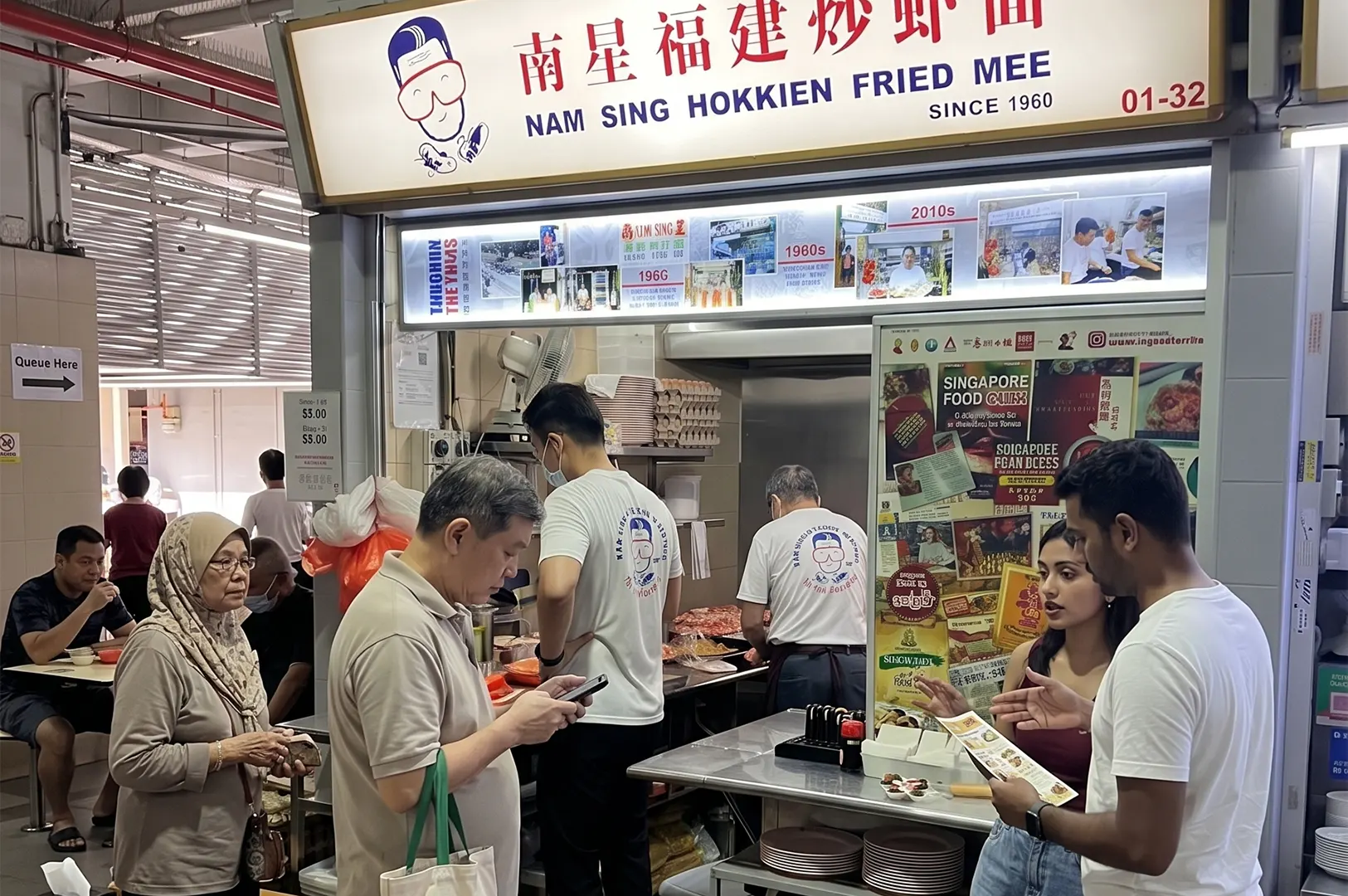 Customers waiting in line at the popular Nam Sing Hokkien Fried Mee stall in a Singapore hawker center.