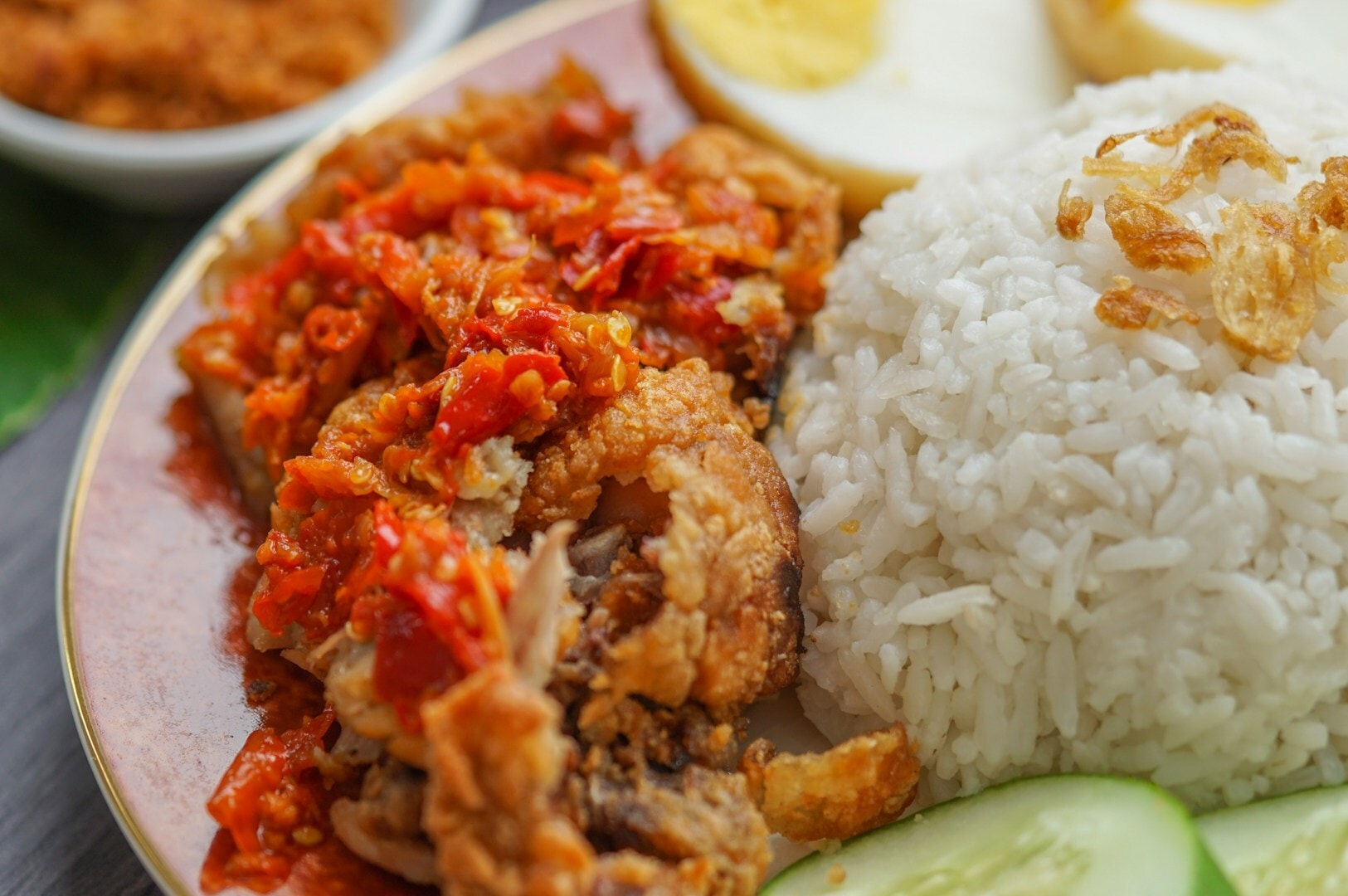 A plate of Malaysian fried chicken, rice, and cucumber from Maxwell Hawker Centre.