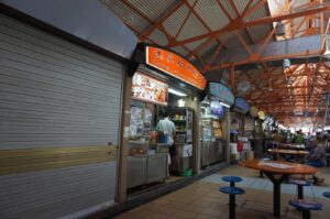 Interior view of Maxwell Hawker Centre's food court, showcasing tables and chairs in a large, open space. Photo by Google.