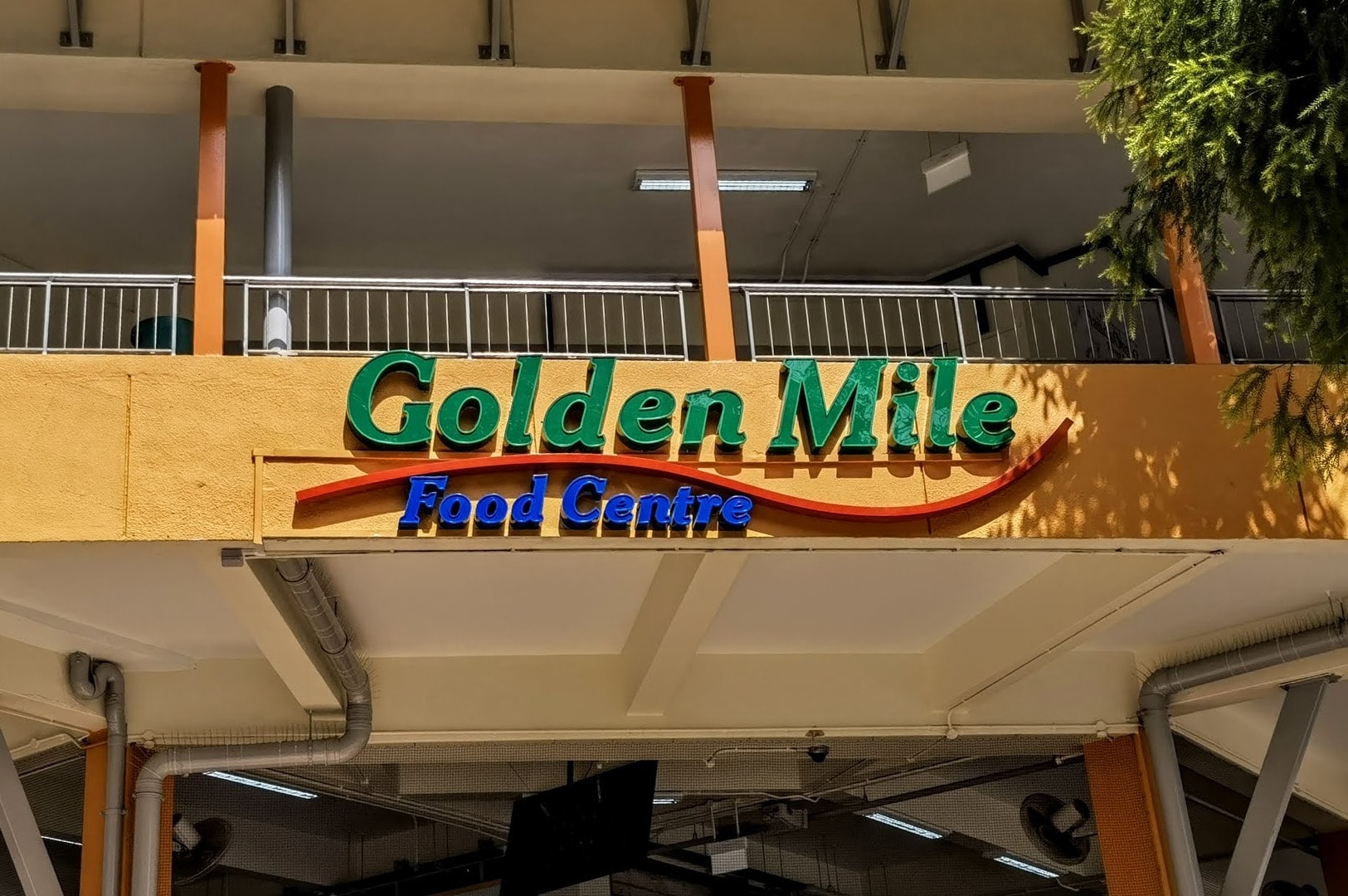Exterior view of Golden Mile Food Centre, showcasing its colorful signage and busy entrance filled with visitors. Photo by Johor Kaki.