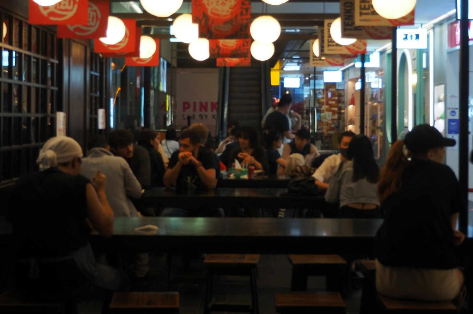 Patrons gathered at tables in Newton Food Centre, sharing food and conversation in a bustling restaurant setting.