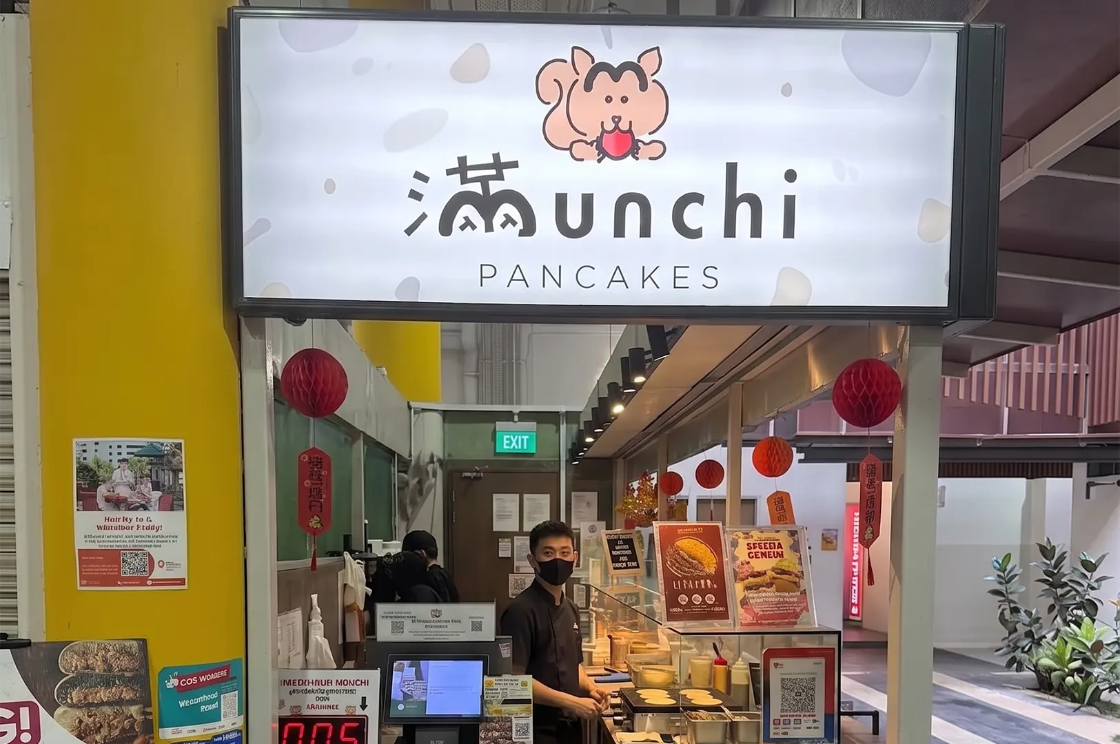 Munchi Pancakes hawker stall with a vendor standing at the counter.
