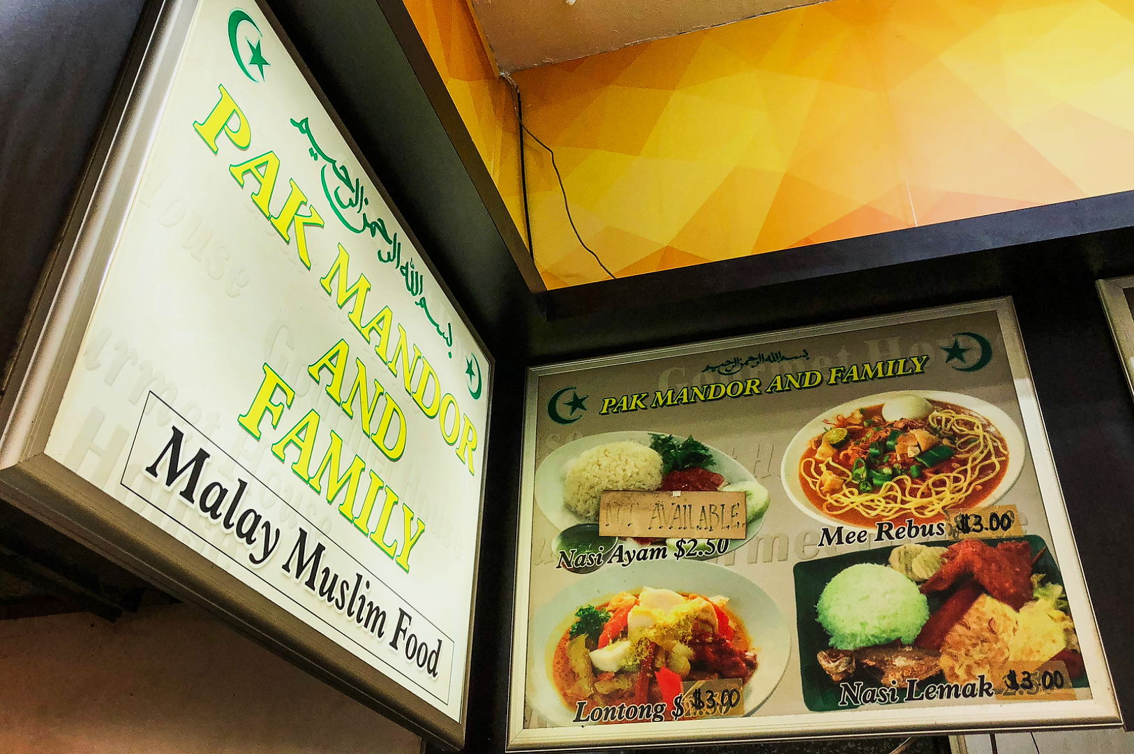 Shop sign for "Pak Mandor and Family" Malay Muslim Food, displaying a colorful menu with dishes like Nasi Ayam, Mee Rebus, Lontong, and Nasi Lemak. Price tags accompany each dish.