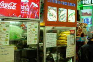 A man stands outside Newton Food Centre holding a Coke and a bag of chips.