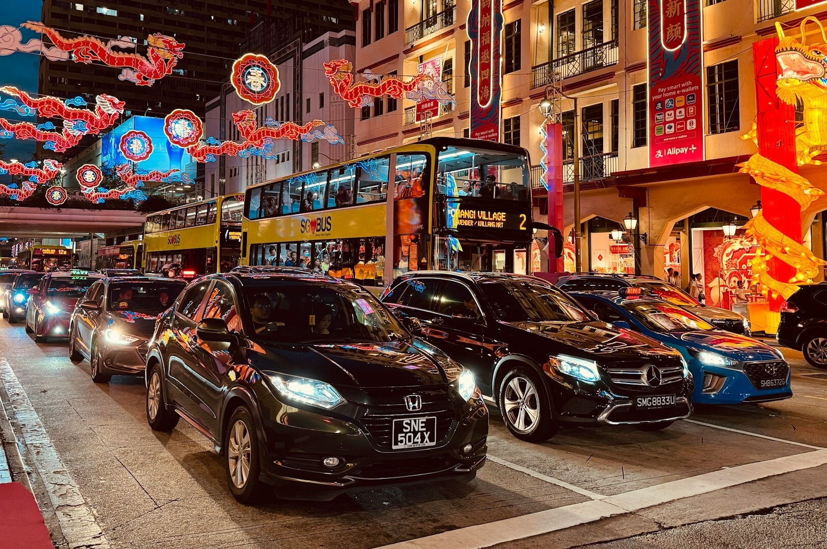 Cars and buses are lined up on a bustling street in Chinatown Complex, illustrating the vibrant city atmosphere.