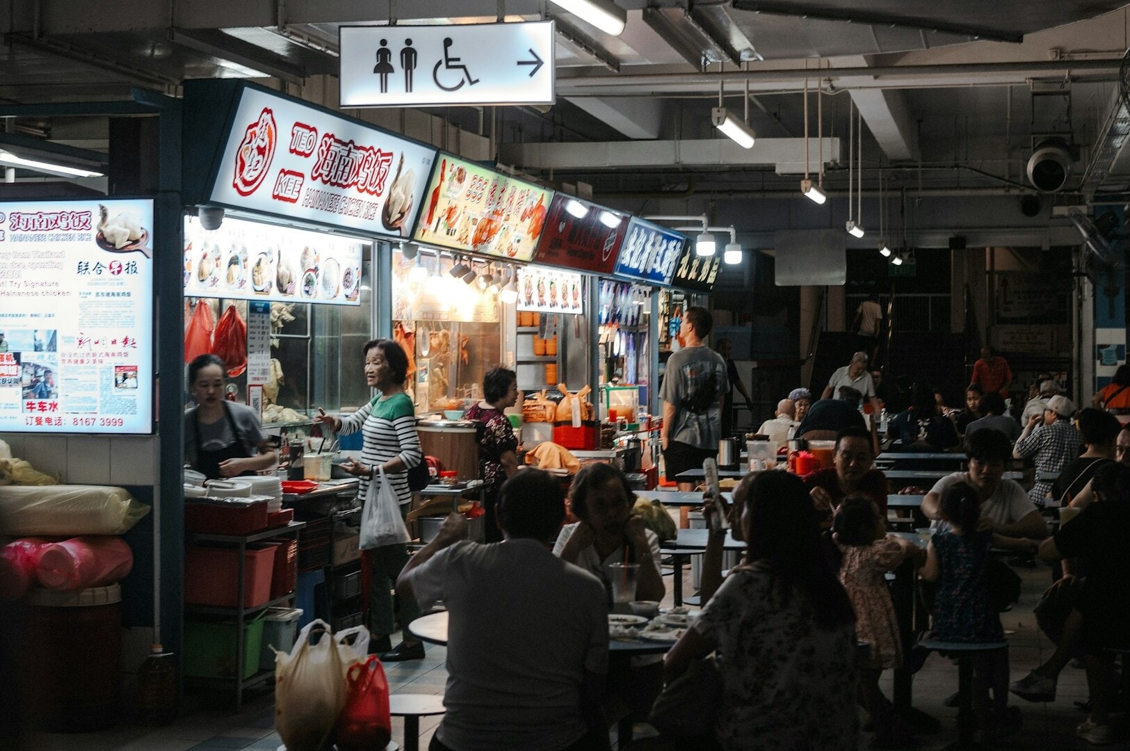 Diners seated at tables in the bustling Singapore Old Airport Road Food Centre.