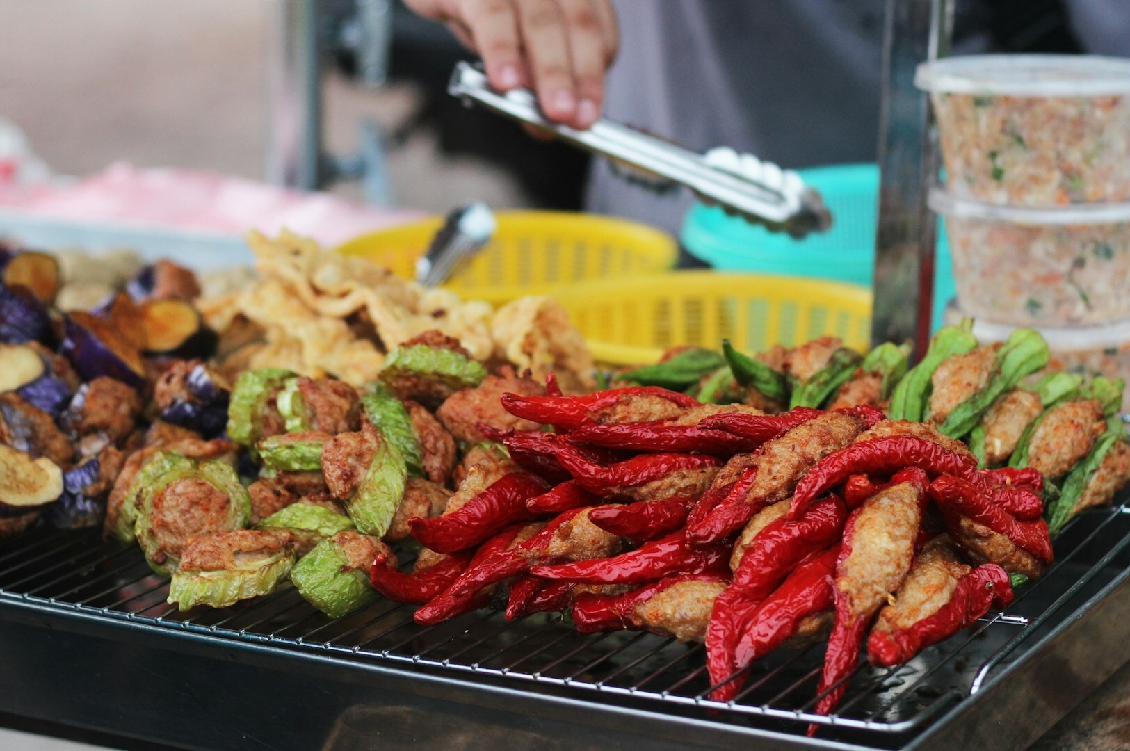 A diverse array of food items grilling at Chinatown Complex, showcasing meats and vegetables on a hot grill.