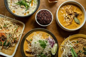 A variety of Thai food dishes displayed on a wooden table at Golden Mile Food Centre.