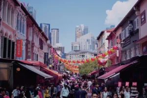 Crowded scene at Chinatown Complex in Singapore, showcasing a diverse group of people walking along the busy street.
