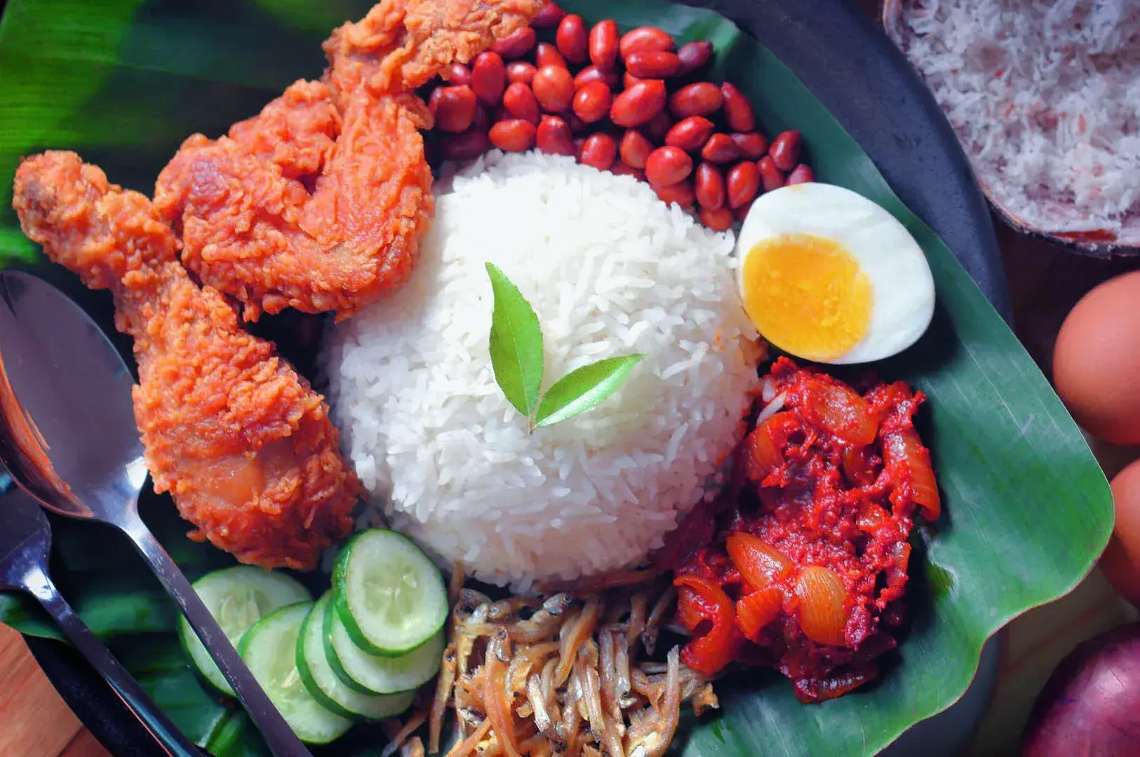 Nasi Lemak on a banana leaf, showcasing rice, chicken, eggs, and beans, from Singapore Old Airport Road Food Centre. Photo by Google.