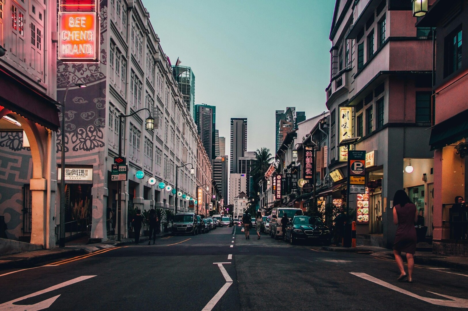 People stroll down a lively street in Chinatown Complex, surrounded by various buildings and shops.