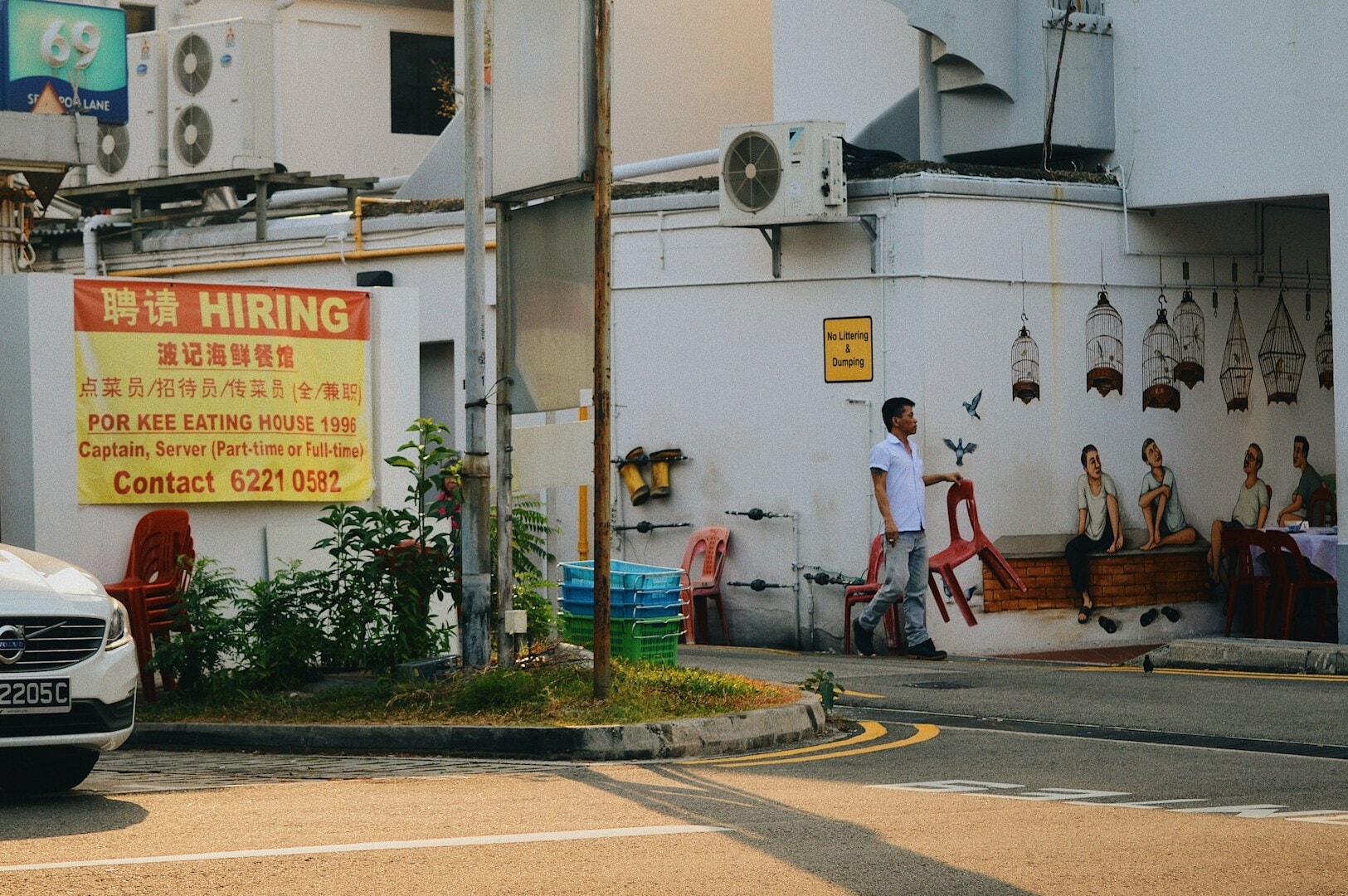 A white car is parked along the street in Tiong Bahru, with nearby trees and typical urban scenery.