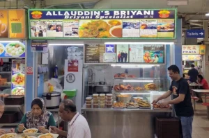Allauddin's Briyani hawker stall at Tekka Centre in Singapore with a vendor preparing food and customers dining.