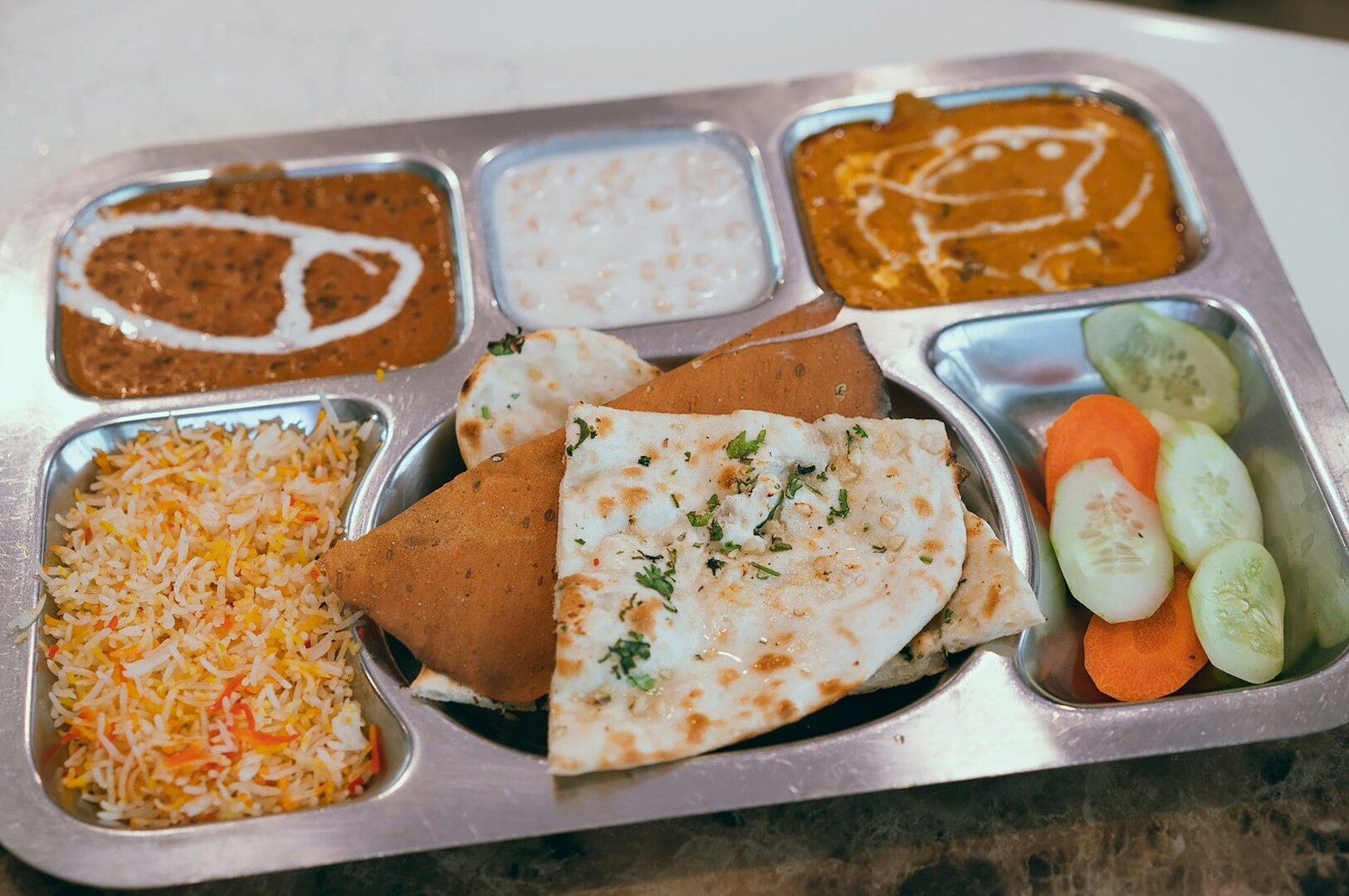 A metal tray displaying an assortment of food items at Tekka Centre, Little India, Singapore.