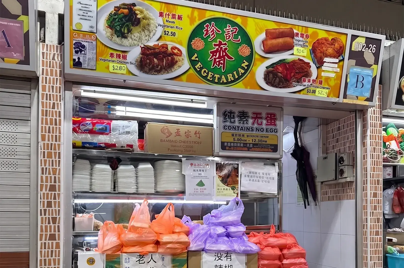 Zhen Ji Vegetarian hawker stall storefront with a yellow menu board displaying egg-free Chinese vegetarian dishes and packed takeout meals.