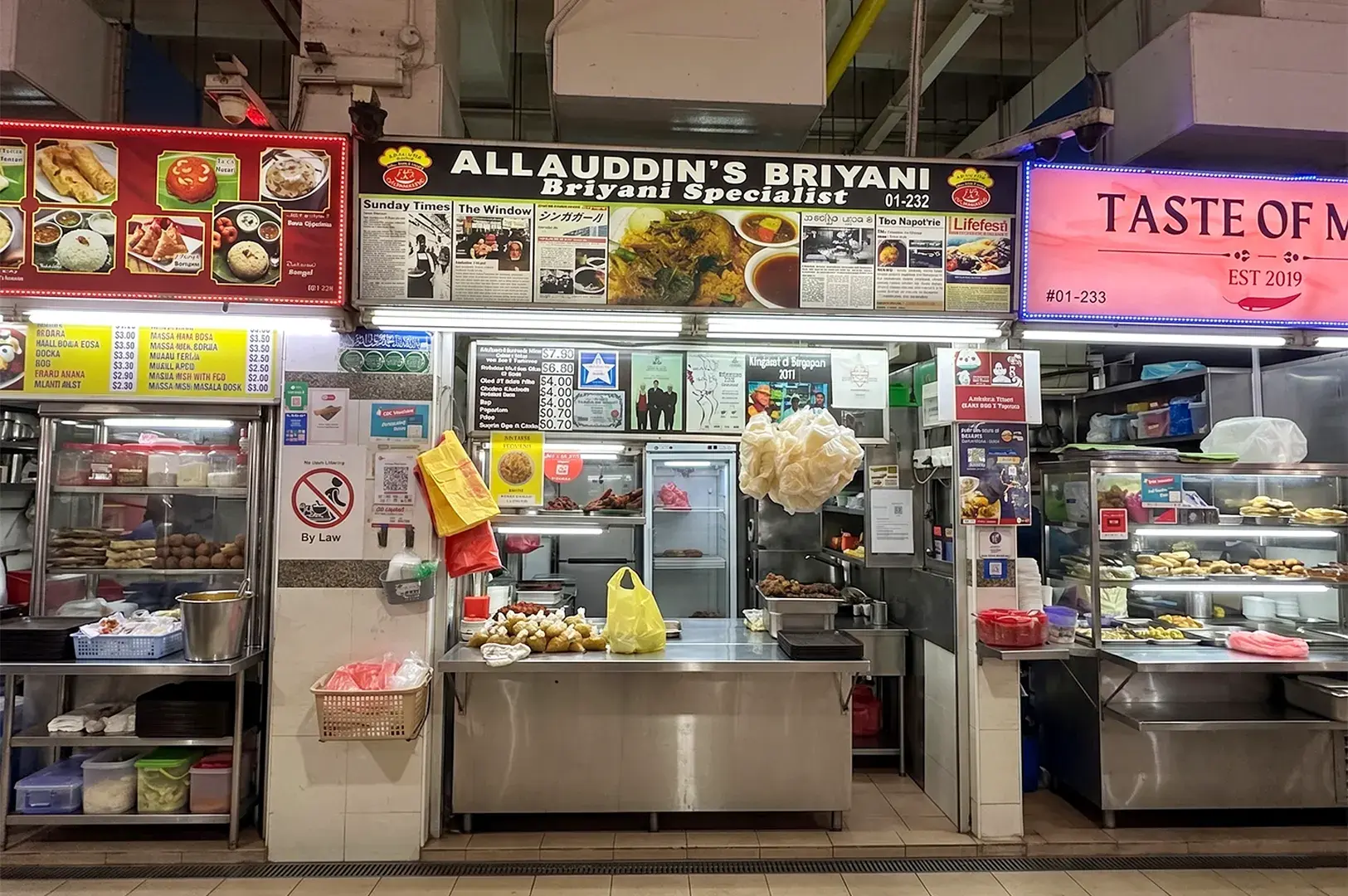 Allauddin's Briyani stall at a Singapore hawker center featuring traditional Indian-Muslim cuisine and menu signs.