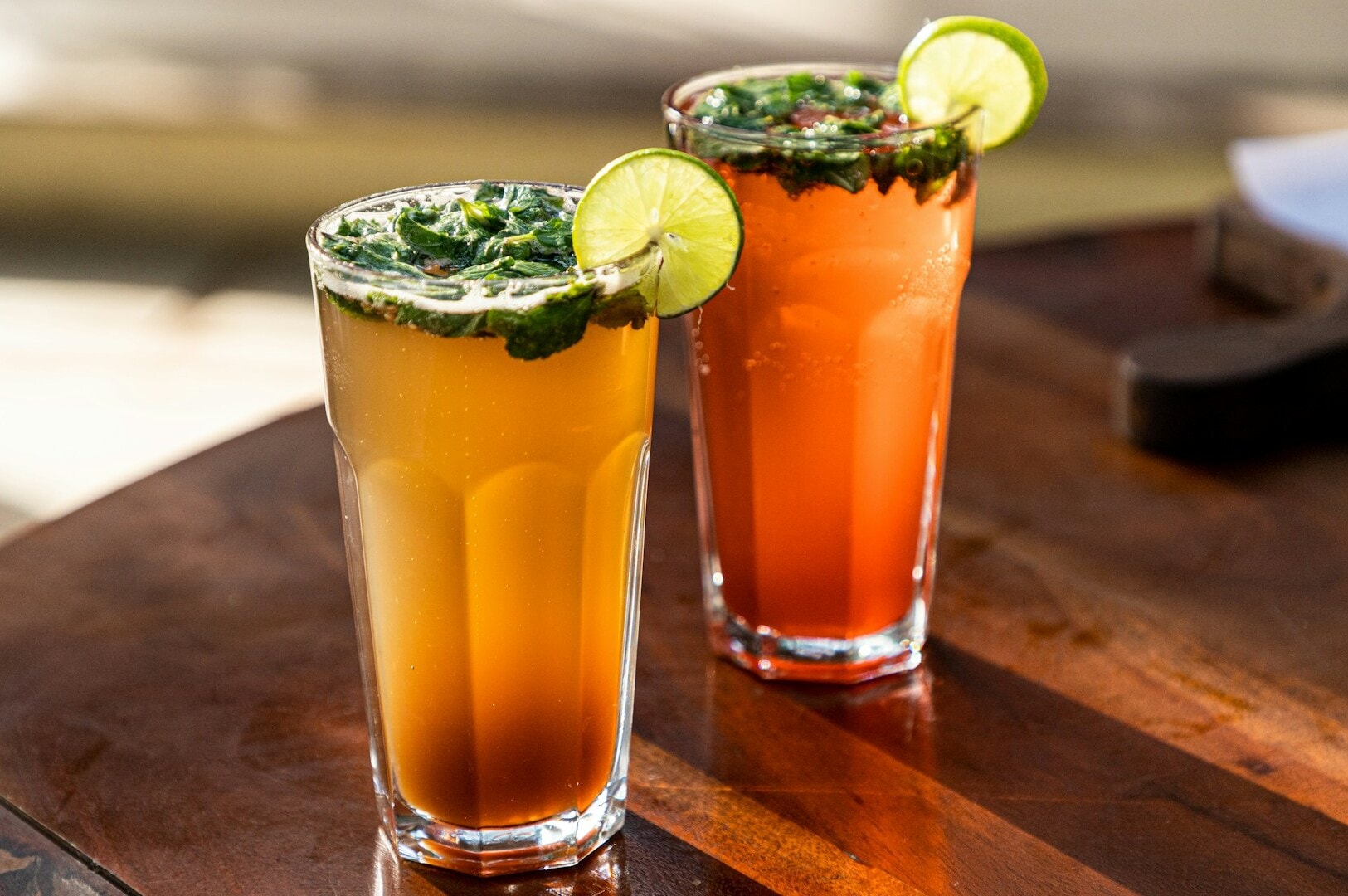 Two refreshing drinks with lime and garnishes, displayed at Tekka Centre in Little India, Singapore, showcasing vibrant colors.