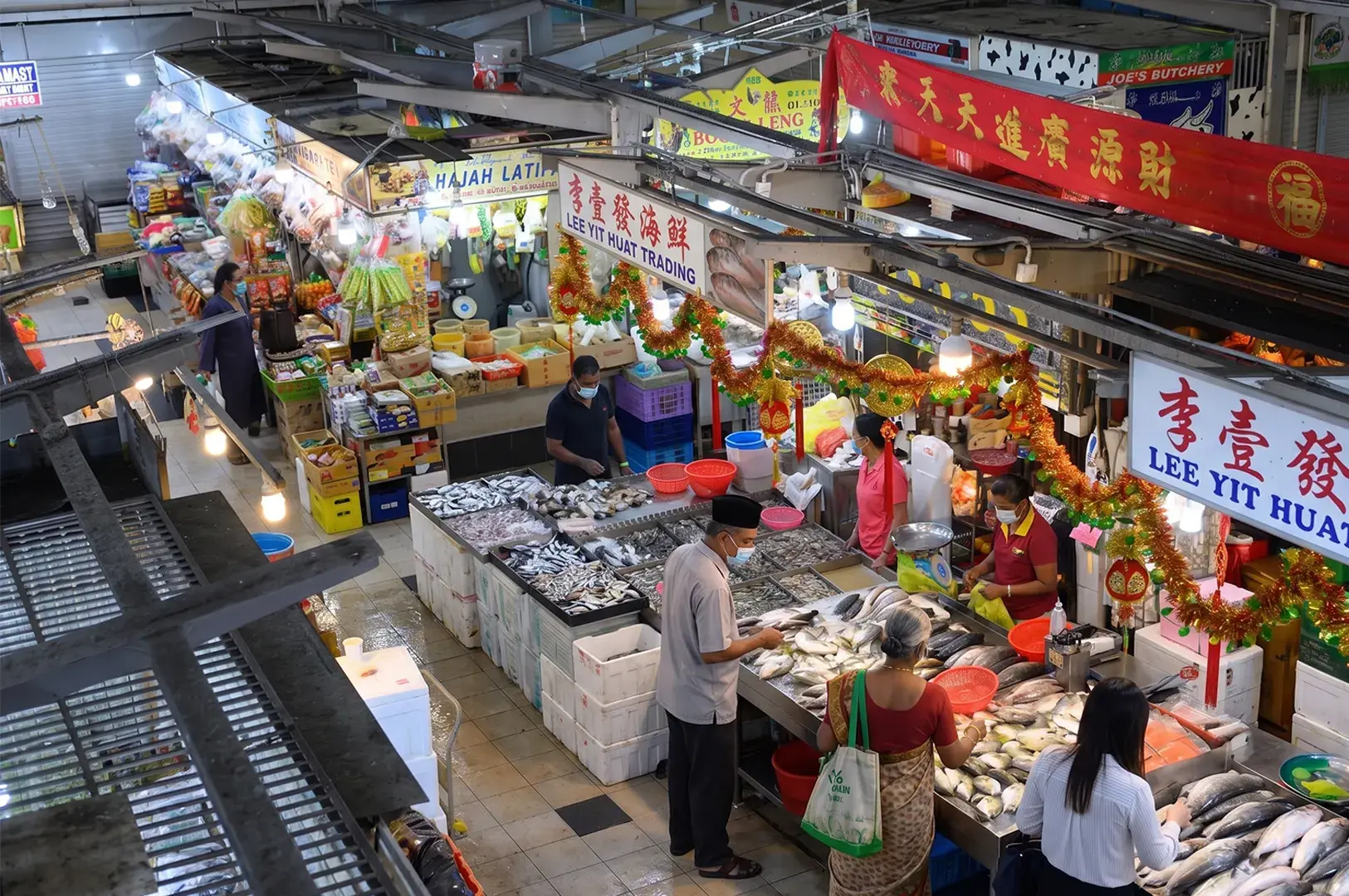 People dining at a Singapore hawker center featuring a Liverpool FC banner and a decorative ox cart display.