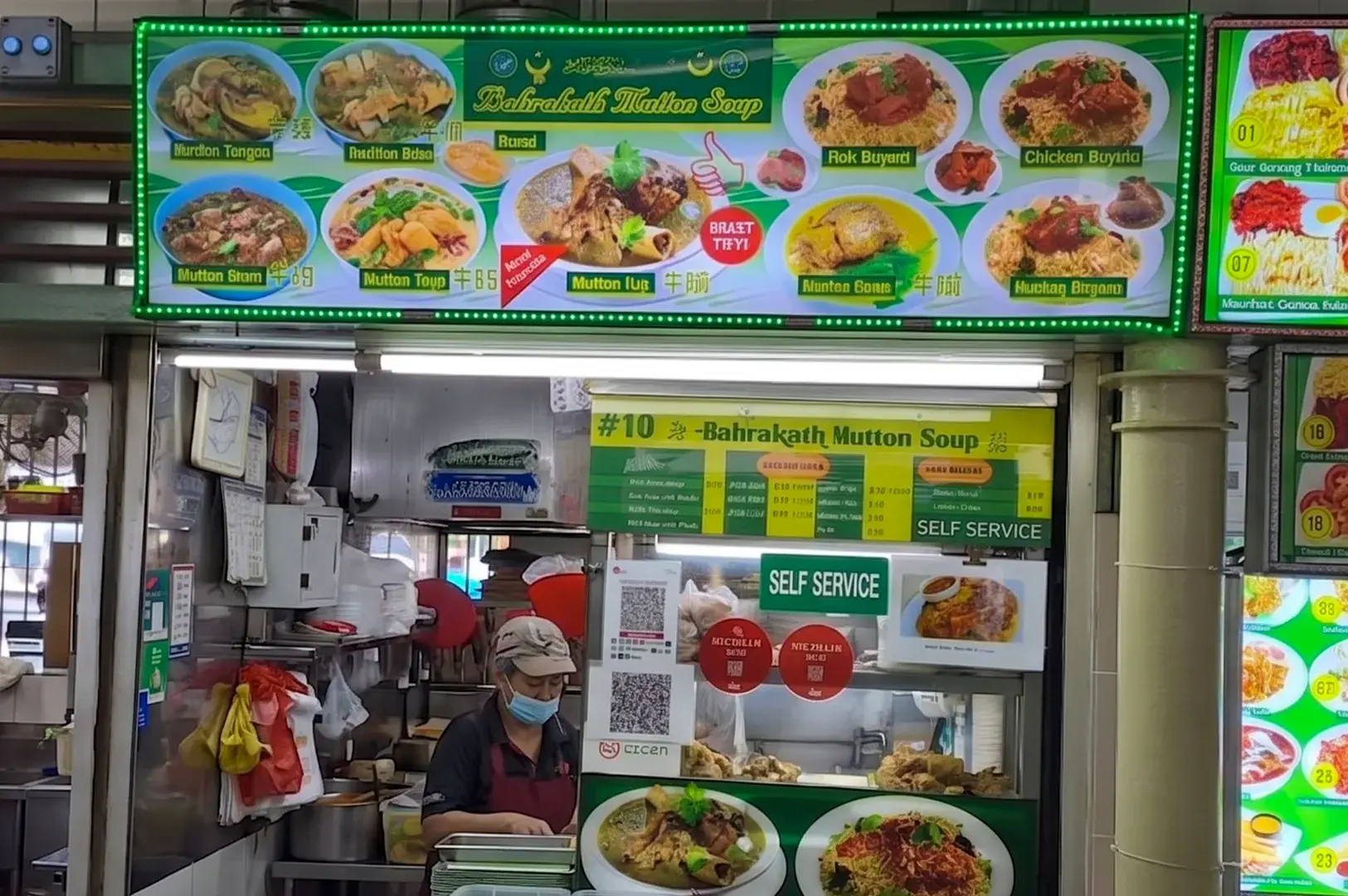 Bahrakath Mutton Soup stall storefront at a hawker center with a bright green menu board showing biryani and soup dishes.