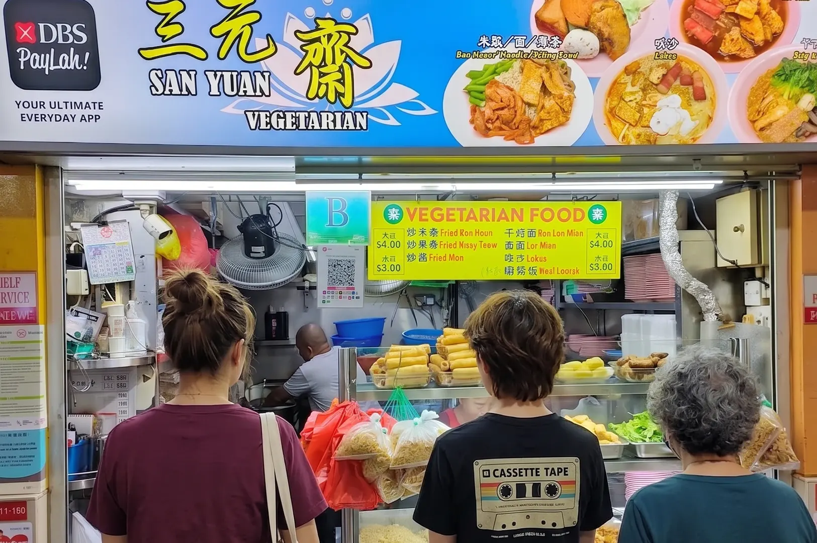 Customers waiting in line at San Yuan Vegetarian food stall in a Singapore hawker center.